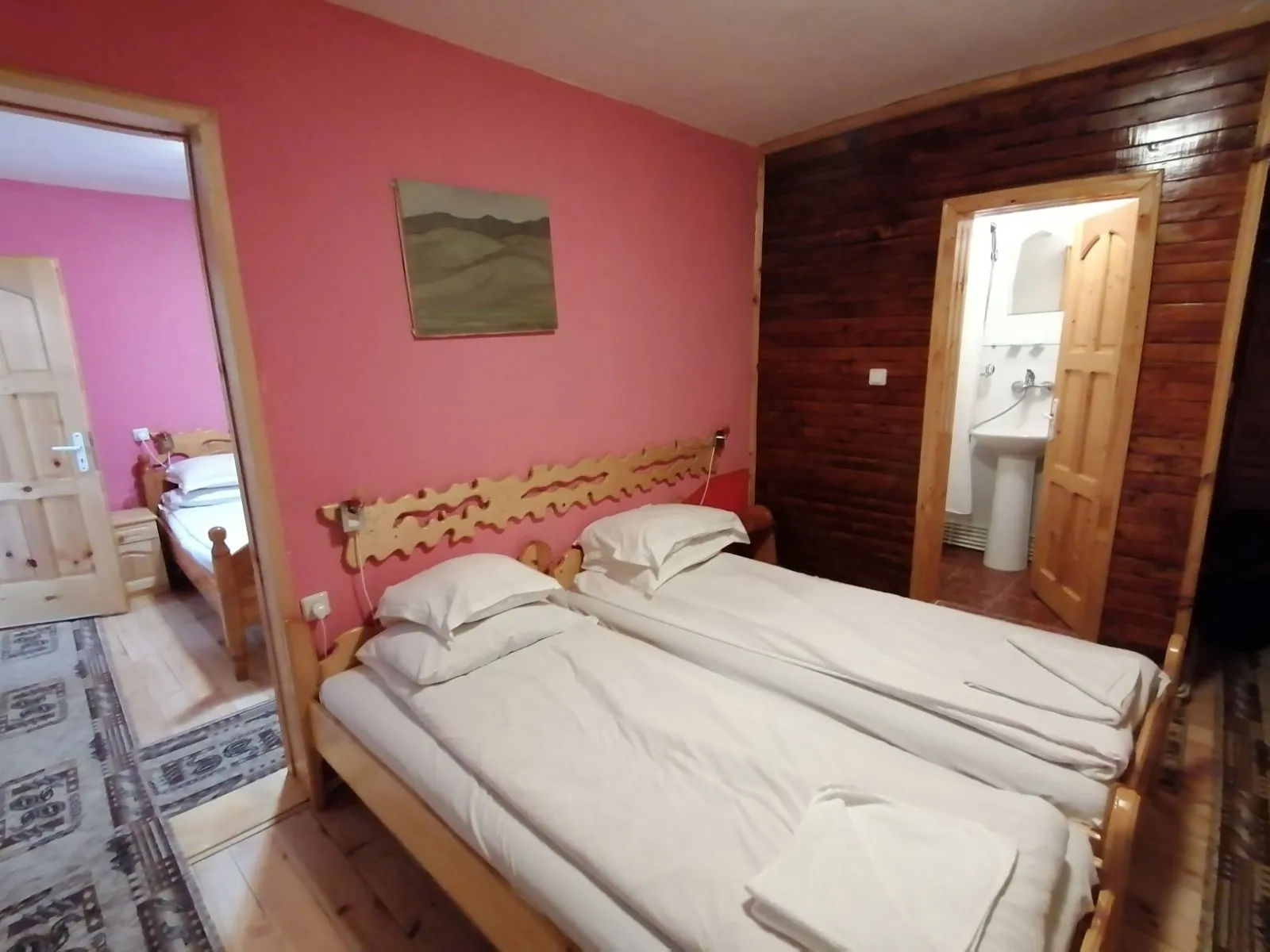 Two beds with a carved headboard and the bathroom