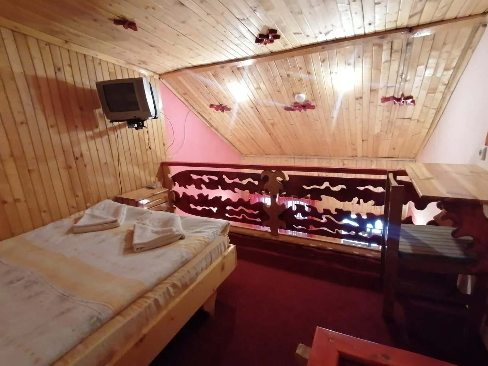 A bed on the upper level, behind a carved railing
